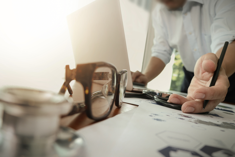 doctor working with laptop computer in medical workspace office and medical network media diagram with stethoscope and eyeglass foreground as concept-1